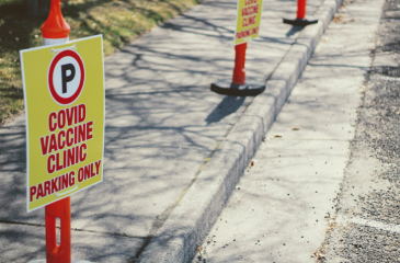 Signs on a curb reading "COVID Vaccine Clinic Parking Only"