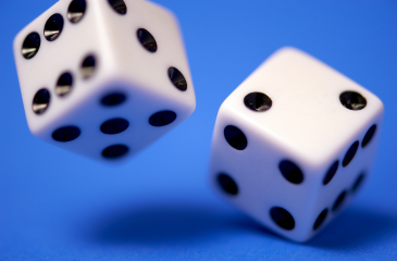 A pair of dice rolling on a blue table
