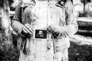 Pregnant woman holding a picture of an ultrasound of her infant.