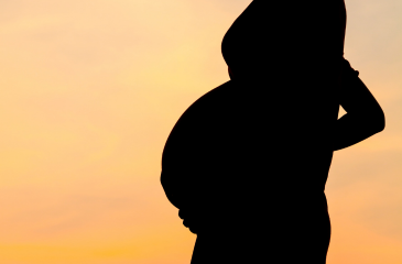 Pregnant person's silhouette in front of a sunset