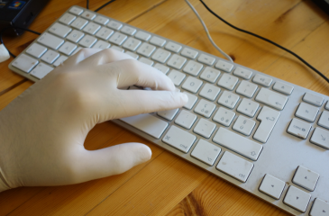 Hand in a latex glove typing on a computer