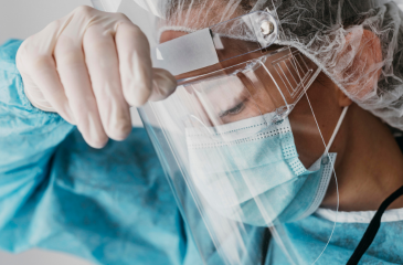 Healthcare worker in PPE running hand across forehead in exhaustion
