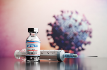A vile of Coronavirus vaccine, a syringe, and a 3D model of the virus