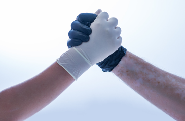Two hands in latex gloves raised and clasped indicating teamwork