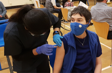 Young person with a mask getting vaccinated at a small rural clinic