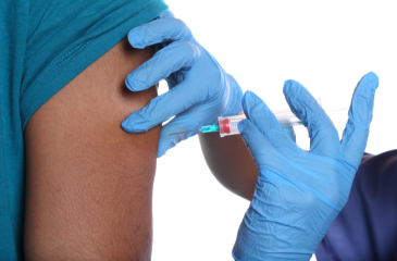 Nurse wearing plastic gloves giving a vaccine in arm of person