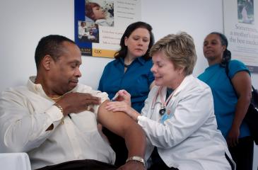 Person of color getting a vaccine in the arm from a nurse