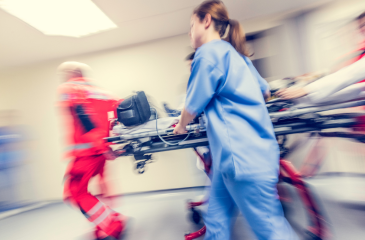 Blurred image of emergency medical professionals rushing a gurney through a hallway