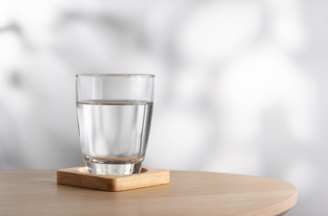 Glass of water on wood coaster and on table